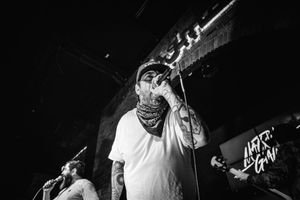 Concert performer singing passionately into microphone on dark stage.