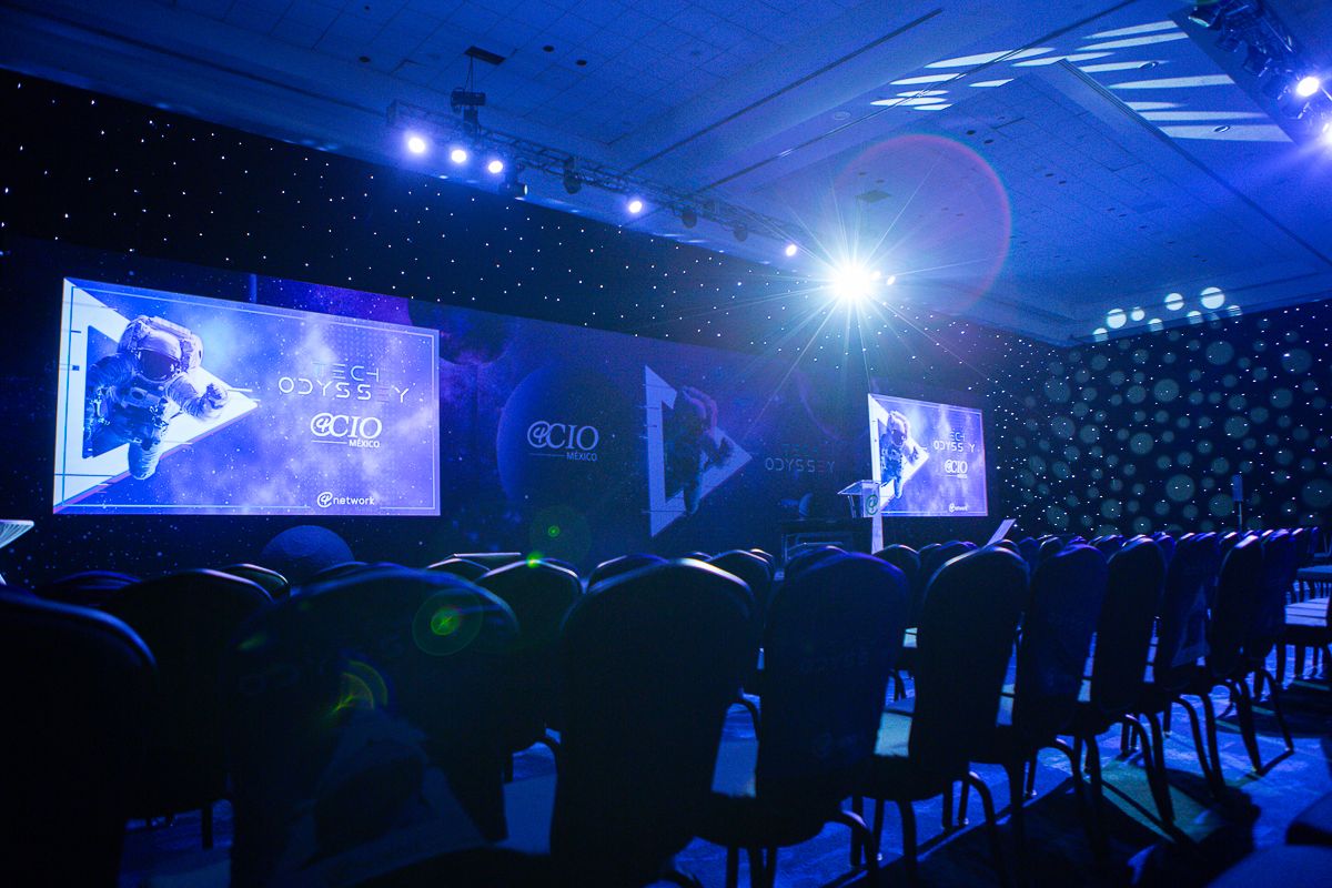 Large conference venue with blue ambient lighting and multiple projection screens.