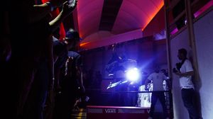 Dark concert venue with silhouettes and dramatic lighting effects creating an atmospheric scene.