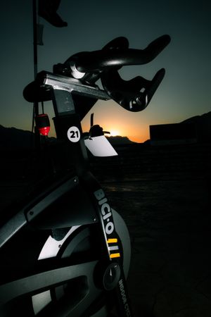 Silhouette of exercise bike against sunset sky creating dramatic contrast.
