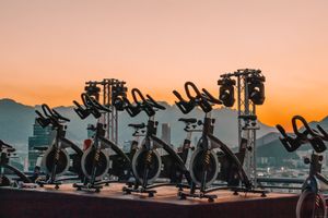 Row of indoor cycling bikes on rooftop at sunset with mountain backdrop.
