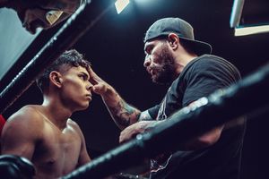 A corner moment during a boxing match with trainer giving guidance between rounds.
