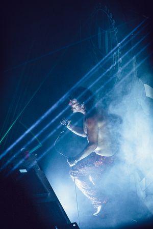 A dramatic performance with a silhouette leaping through smoky blue stage lighting.