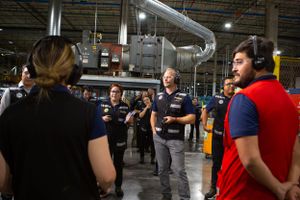 Staff members gathered for training or discussion in a manufacturing warehouse setting.