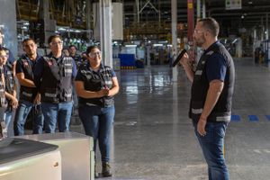 Speaker addresses a small group in a warehouse setting during a corporate event.