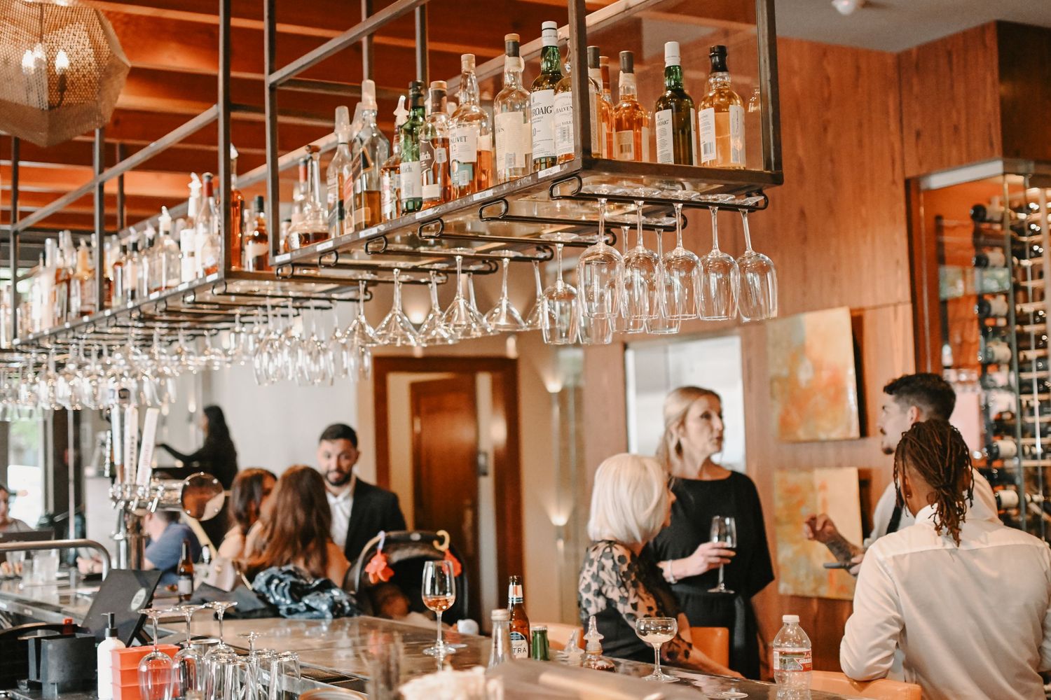 Modern bar interior with hanging wine glasses and wooden accents.