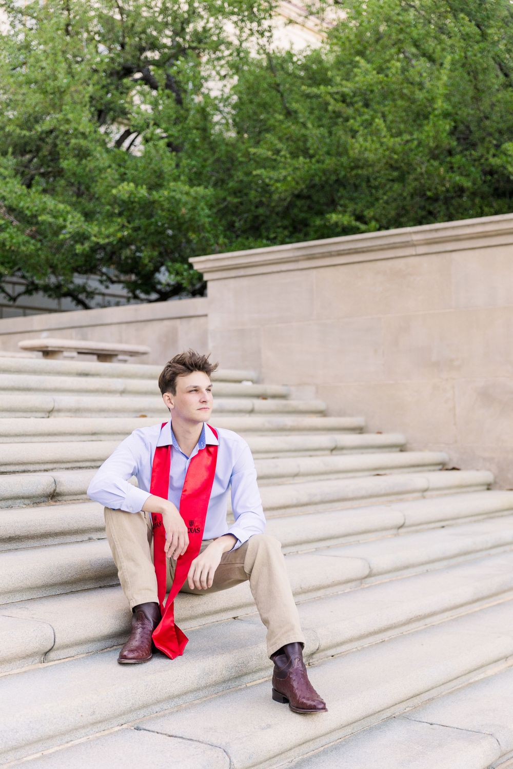 male college graduate sitting on campus cement stairs