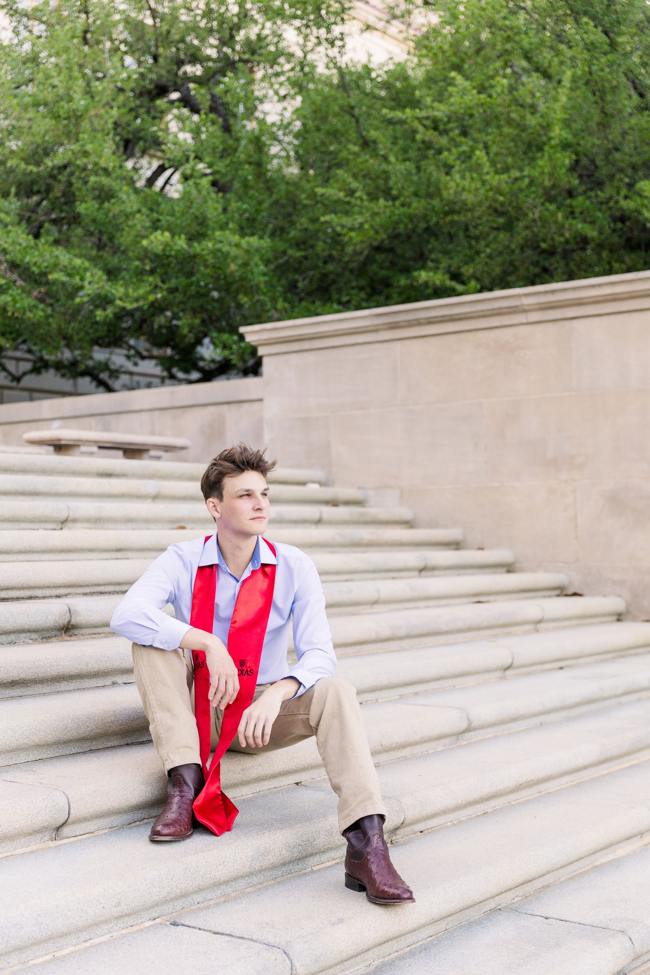 male college graduate sitting on campus cement stairs