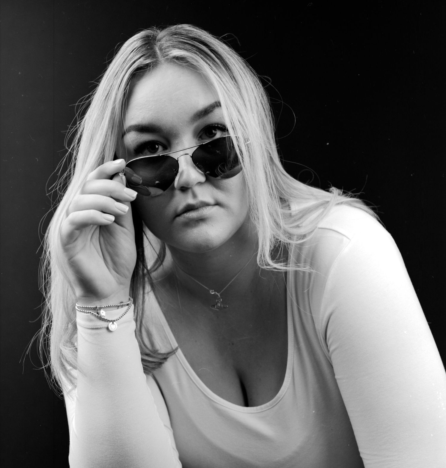 Black and white head and shoulders portrait photograph of young lady wearing sun glasses captured in the studio