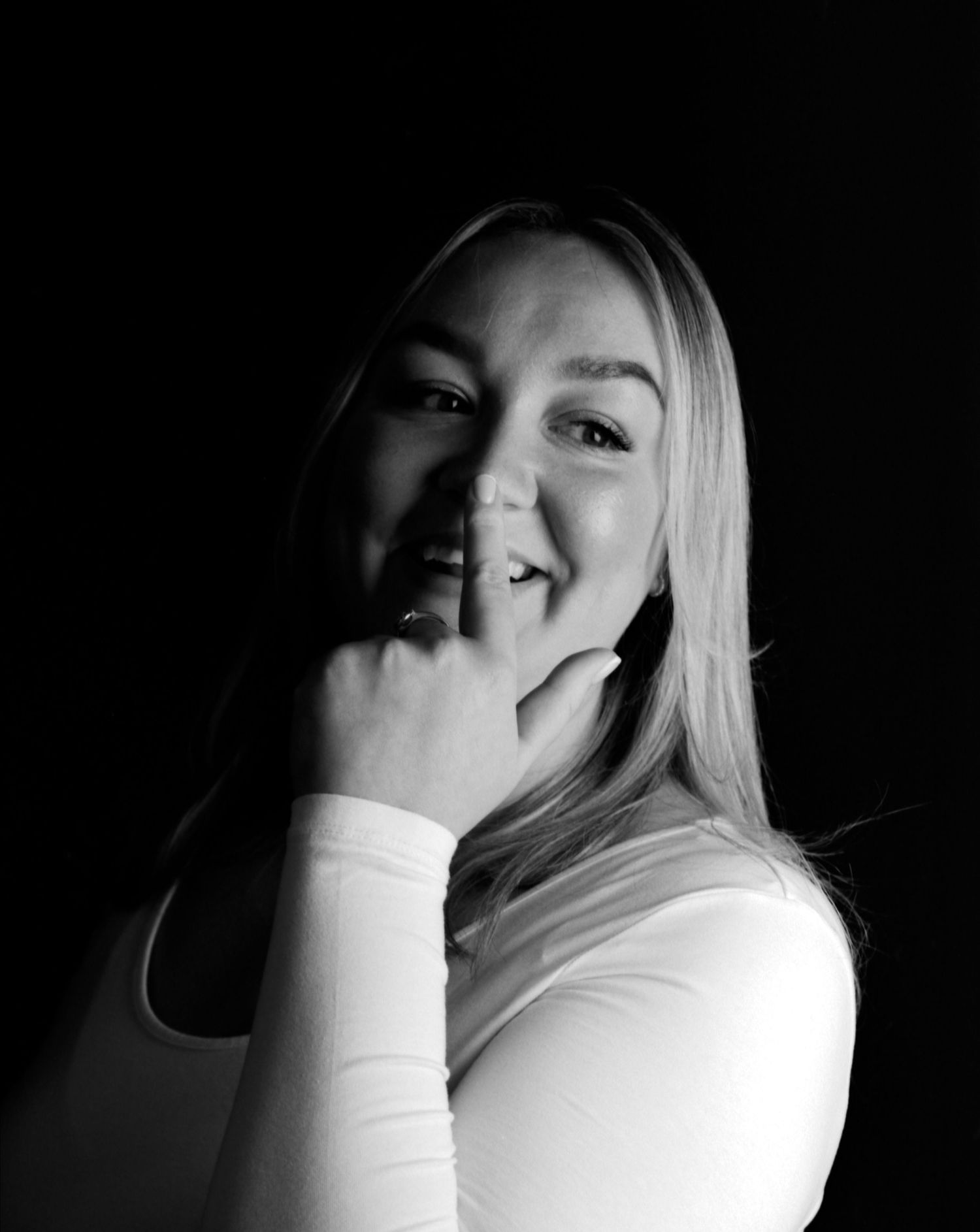 Black and white head and shoulders portrait photograph of young lady laughing captured in the studio