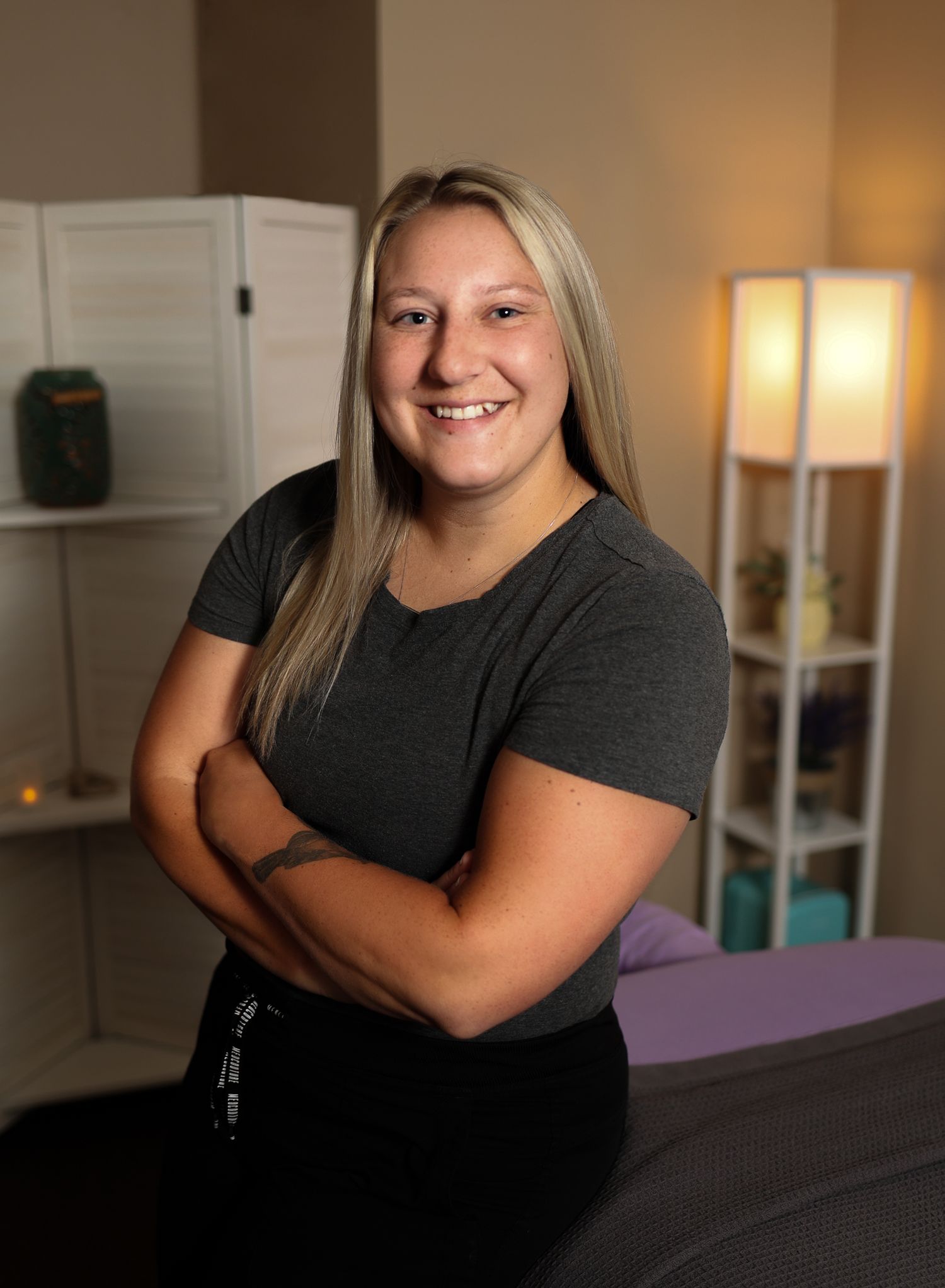 Professional portrait in a massage therapy room with warm lighting and modern decor.