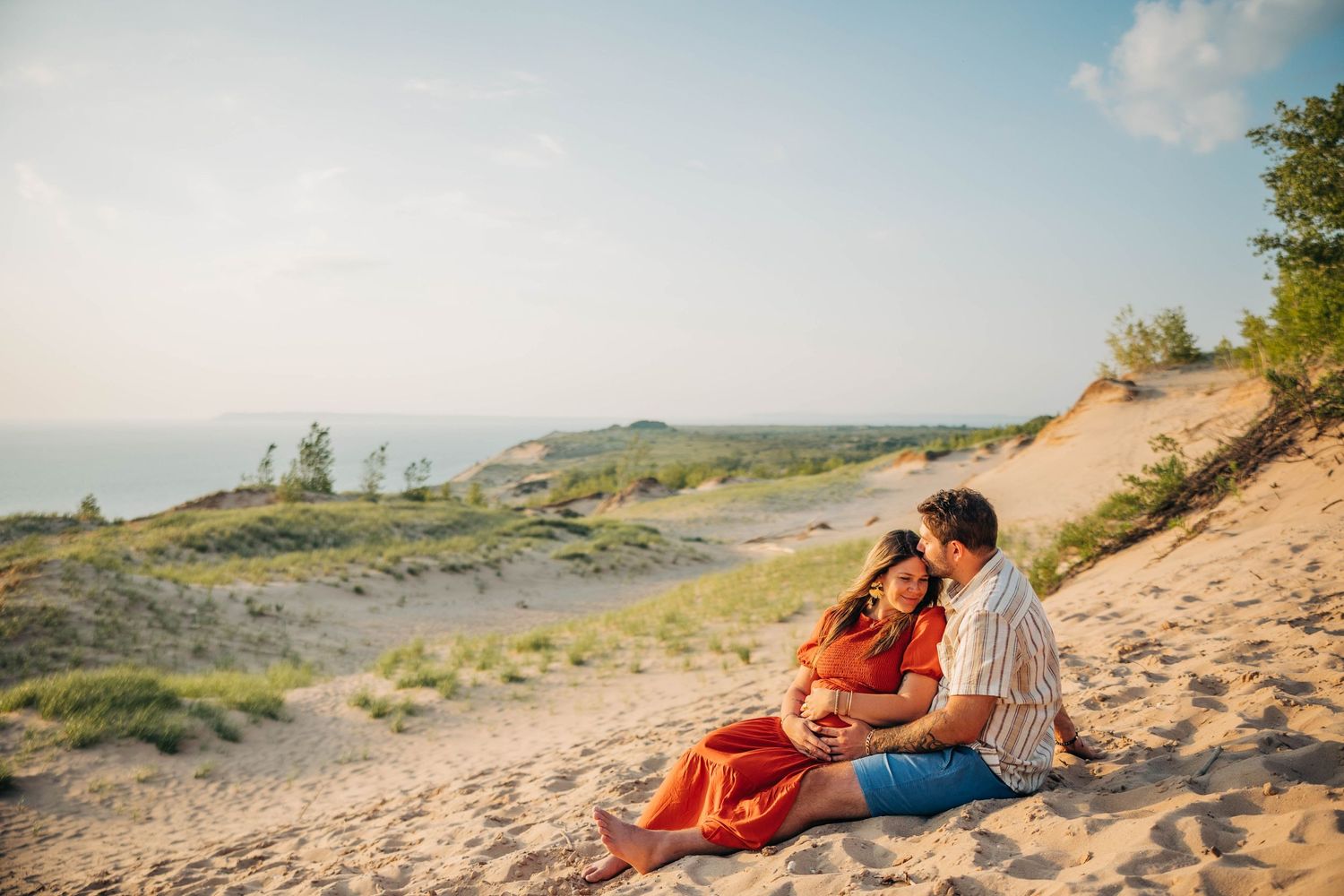 A couple embracing their unborn baby pregnant woman Sleeping Bear Sand Dunes Leelanau Michigan Captured By Grace Hudson