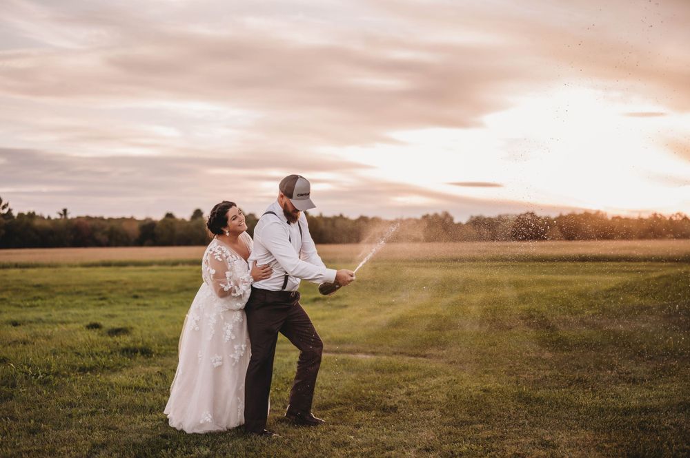Wedding couple dancing in open field during golden hour sunset.