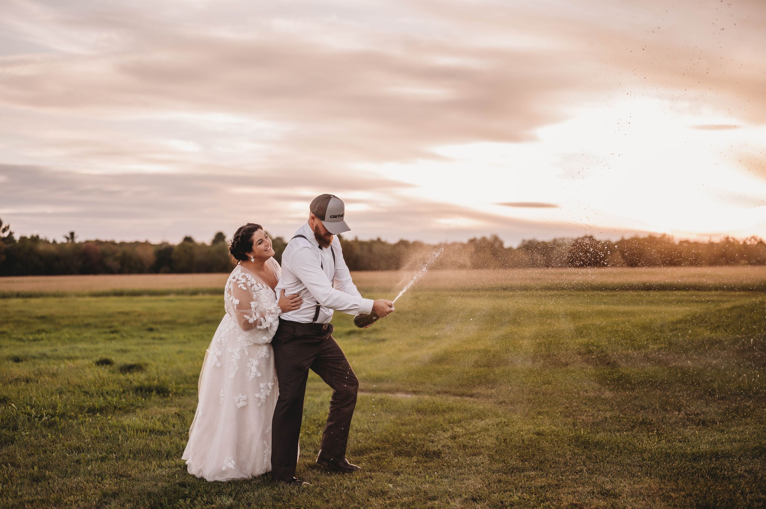 Wedding couple dancing in open field during golden hour sunset.
