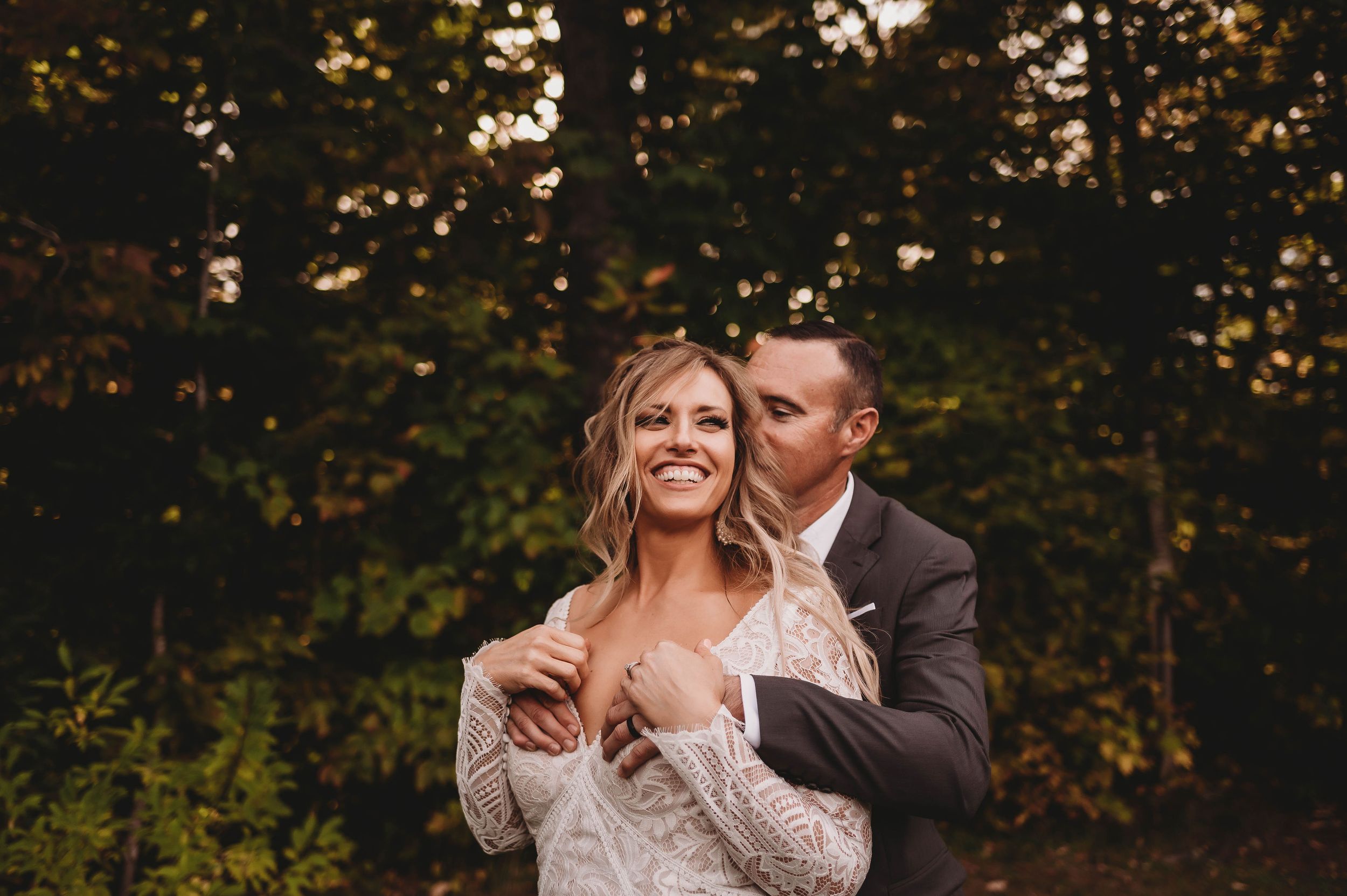 Intimate autumn forest wedding moment with soft golden light filtering through trees.