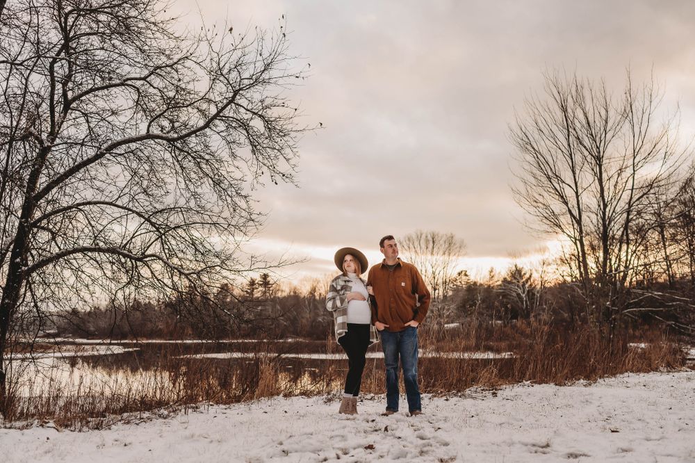 A winter landscape photo of figures walking through snow-covered ground at sunset.