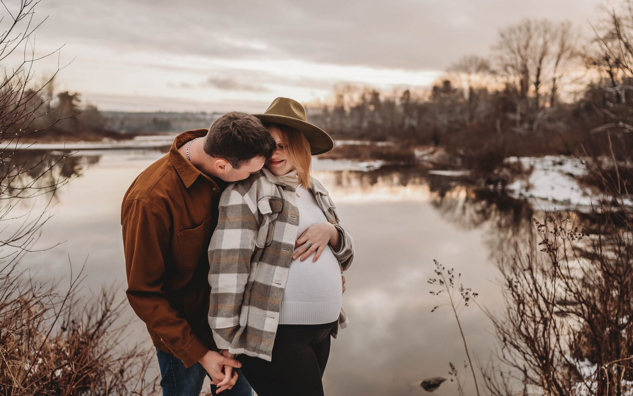 Intimate waterfront moment captured during sunset with a snow-covered landscape in the background.