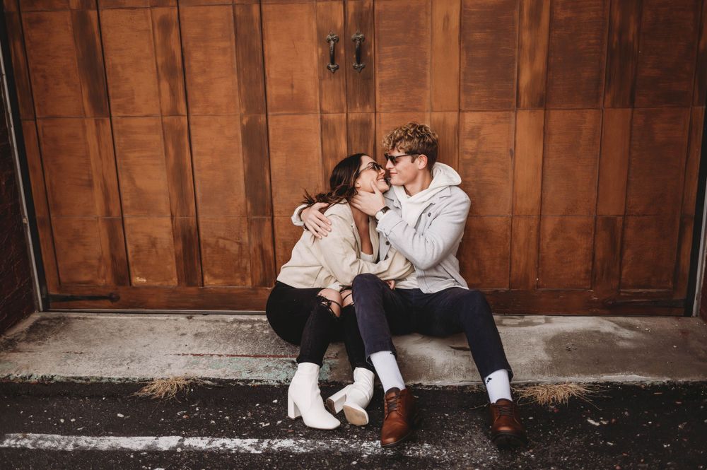 Cozy engagement portrait session against rustic wooden barn door background.