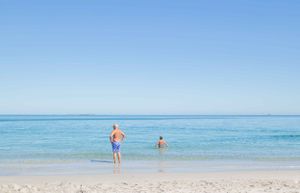 People enjoying a swim in crystal clear turquoise waters at a pristine beach.