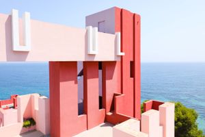Pink and coral colored modern architectural structure overlooking blue ocean waters.