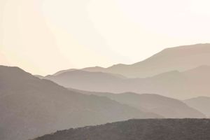 Misty mountain ranges creating layers of silhouettes at sunset.