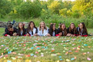A group lies on a blanket covered in confetti during an outdoor photo session.