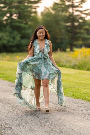 Person twirling in flowing blue-green dress on a sunset path.