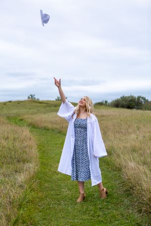 A graduation celebration photo with cap being tossed into the air on a hilltop.
