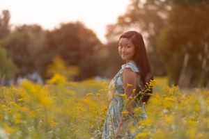 Person in flowy dress standing among yellow wildflowers at golden hour.