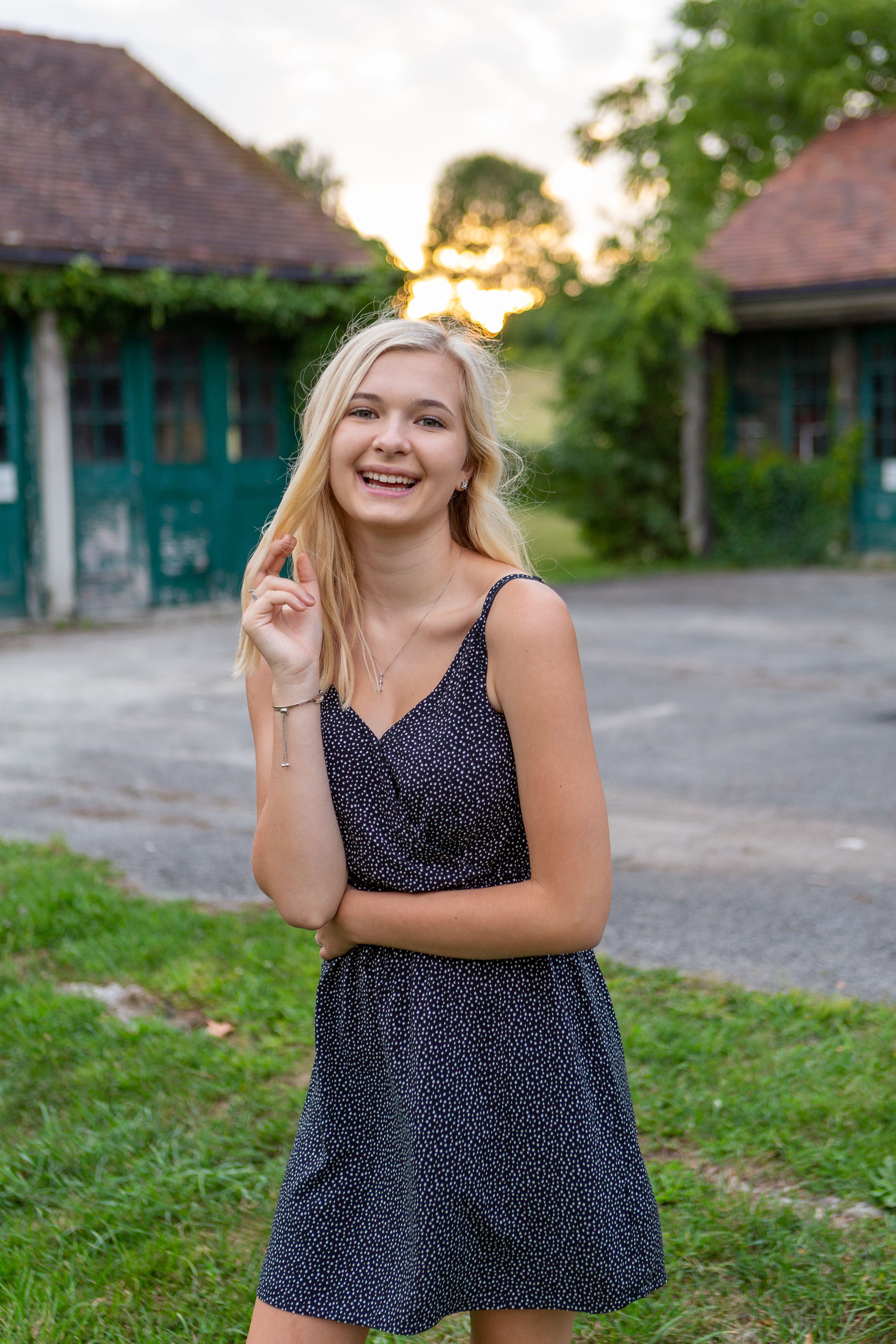 Person in polka dot dress posing outdoors at sunset near vintage buildings.