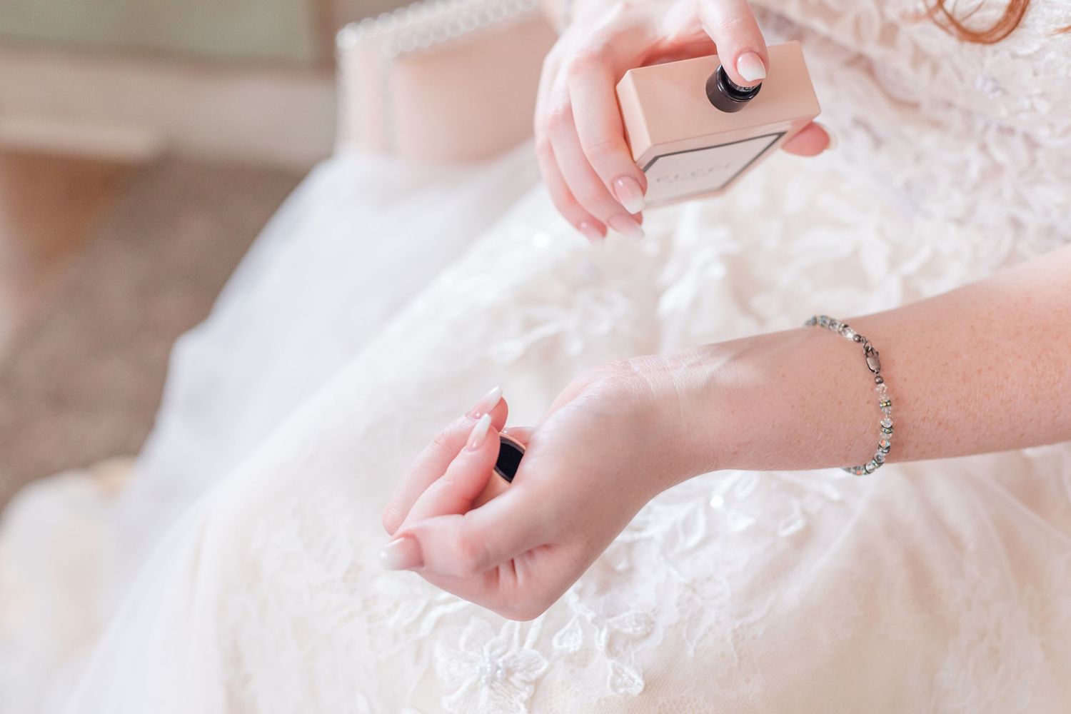 Close-up of hands adjusting delicate lace details on a white wedding dress.