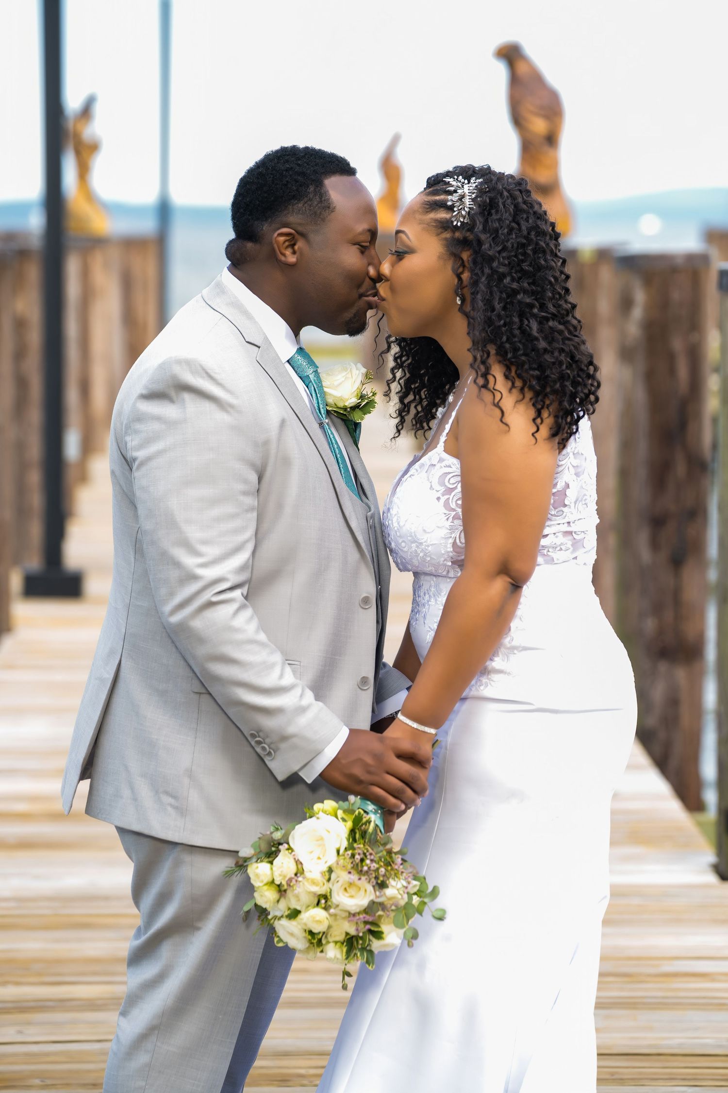 A romantic moment between newlyweds on a wooden dock by the water.