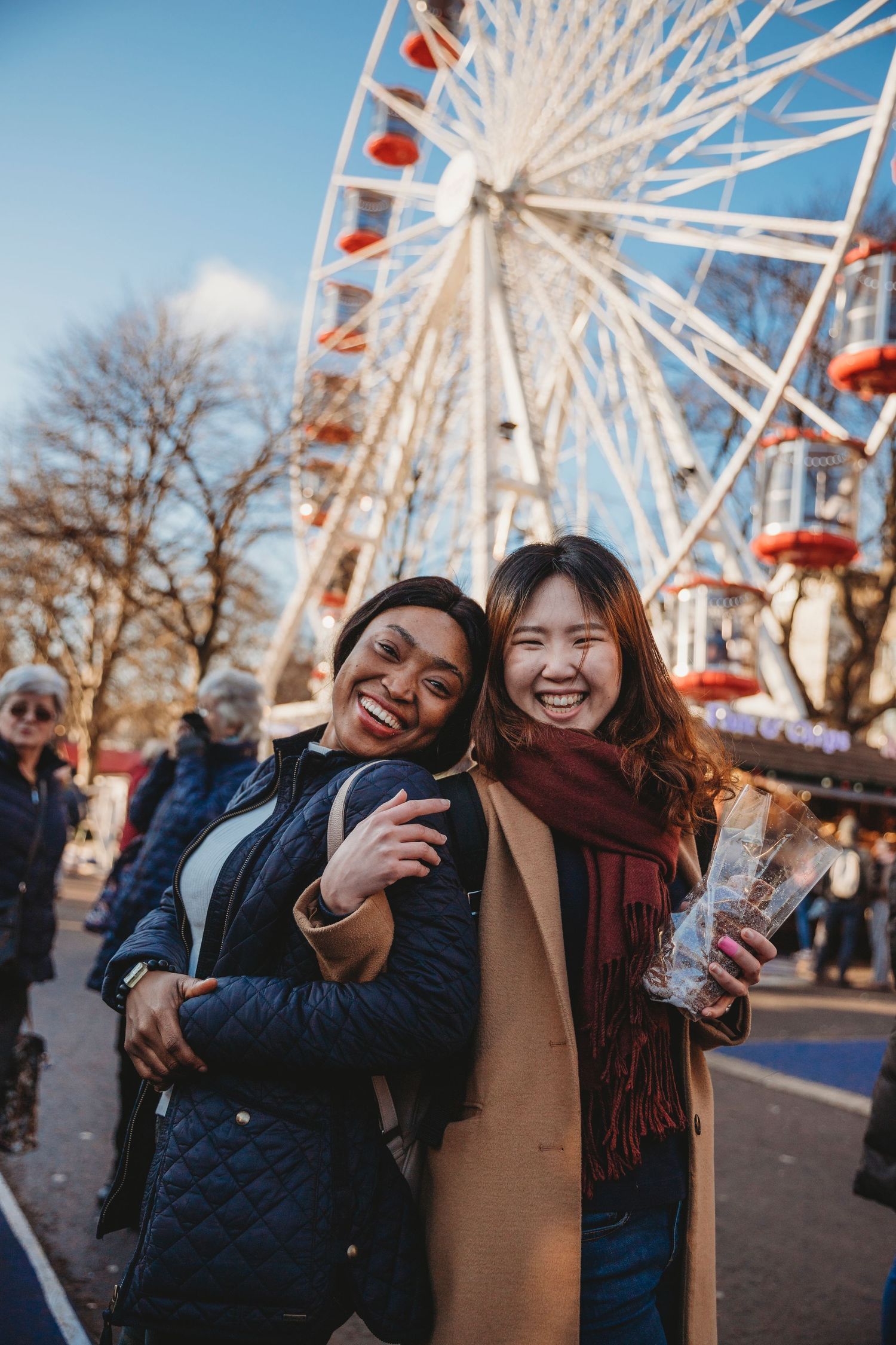 Friends enjoying a winter carnival with a Ferris wheel in the background.