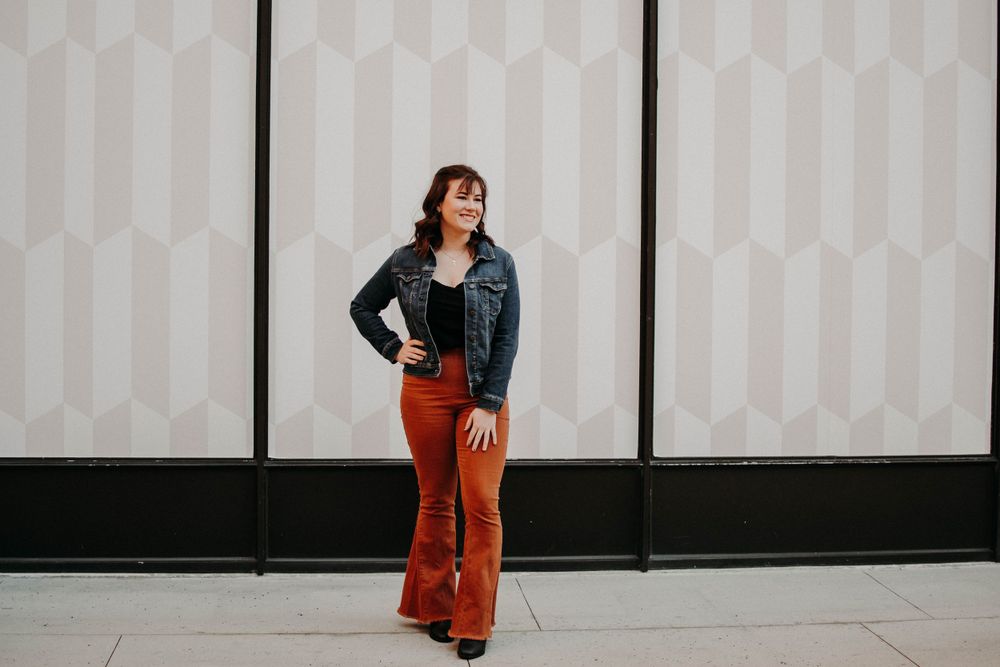 Fashion portrait against geometric wall featuring vintage-inspired outfit with flared pants.
