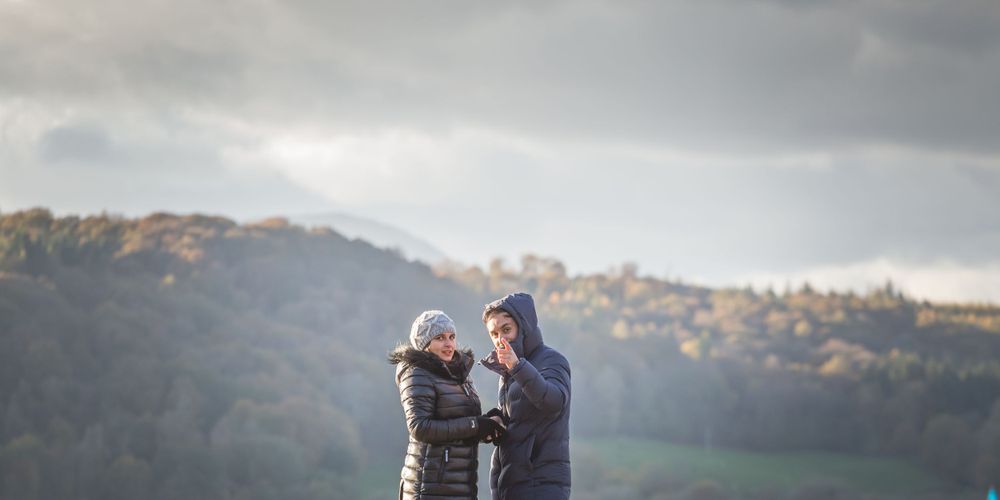 Two people share a romantic moment on a dock with misty mountains in the background.