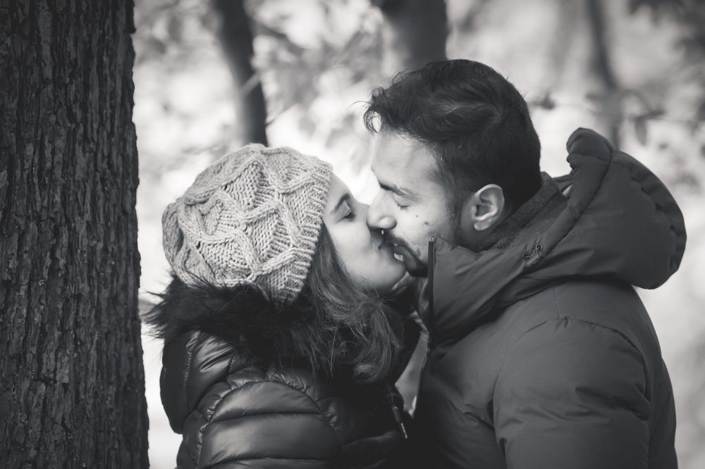 A romantic black and white photo of a couple sharing an intimate moment in winter coats.