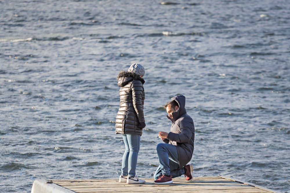 Two people sharing a moment on a wooden dock by a lake.