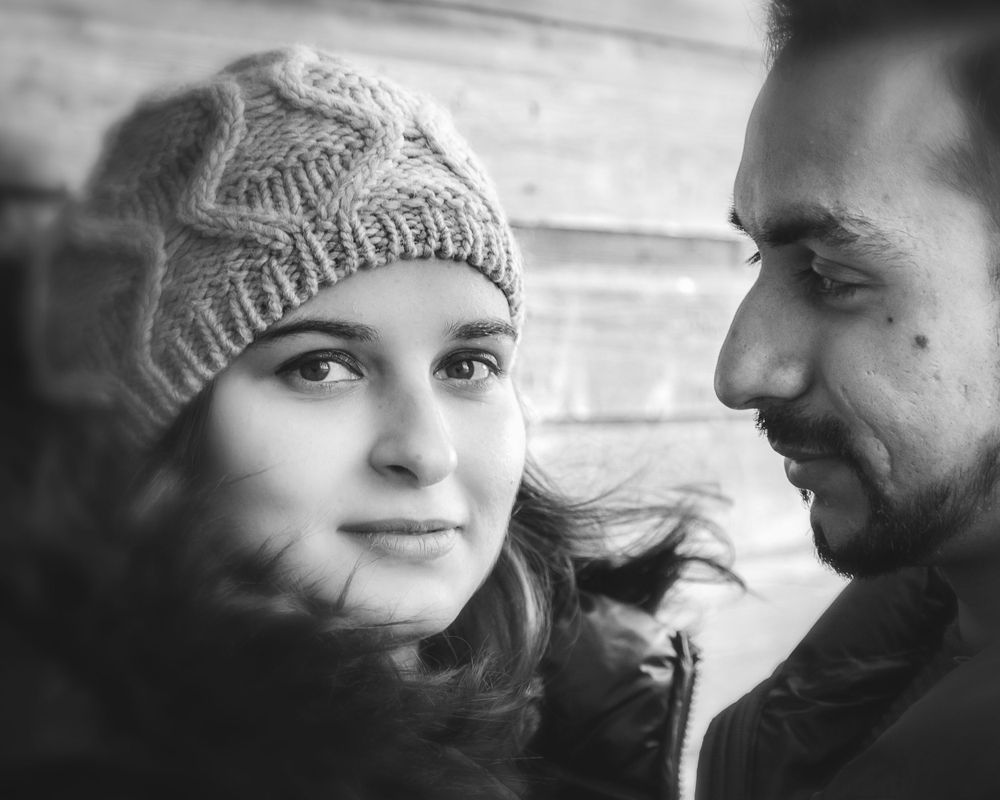 An intimate black and white portrait of a couple wearing winter clothing.