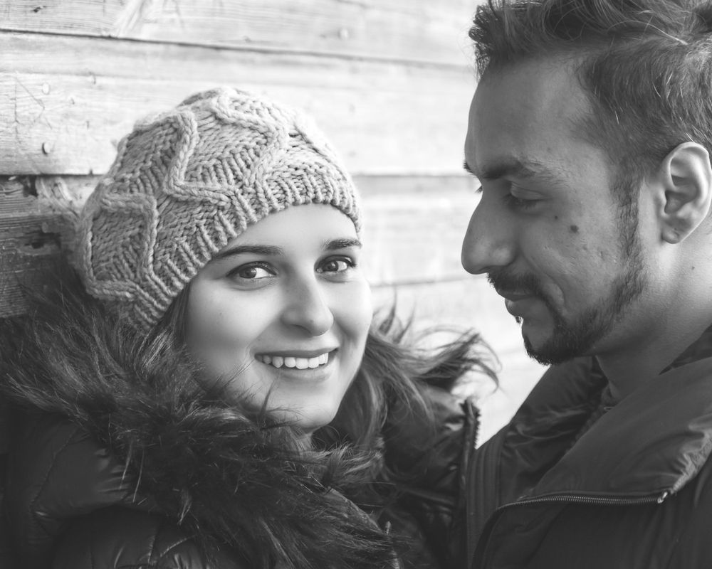 A black and white portrait capturing a tender moment between a couple in winter attire.