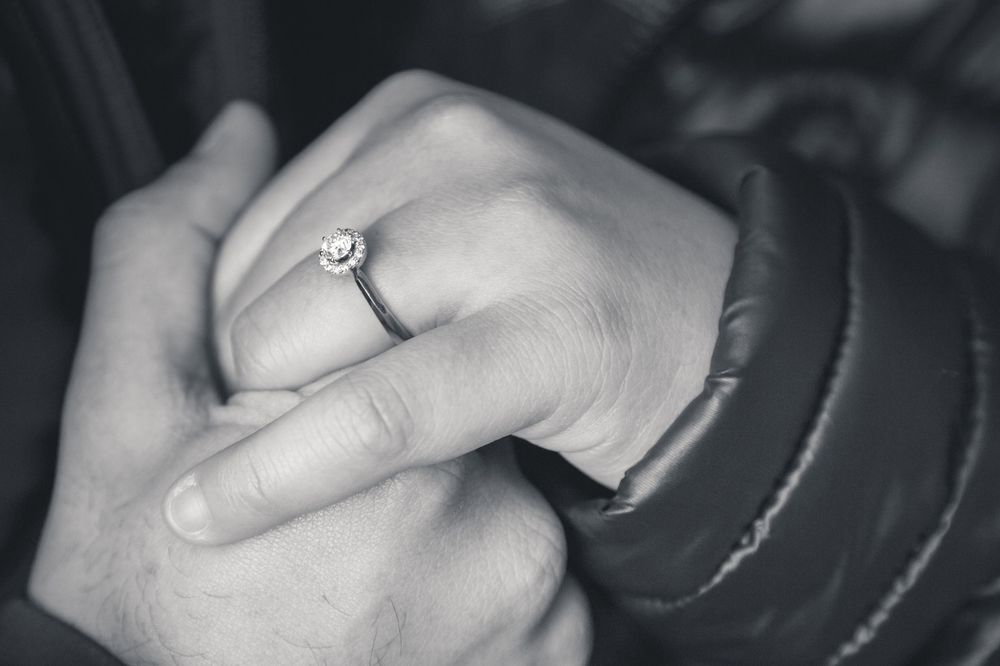 Close-up shot of hands showing off an engagement ring against a puffy winter coat.