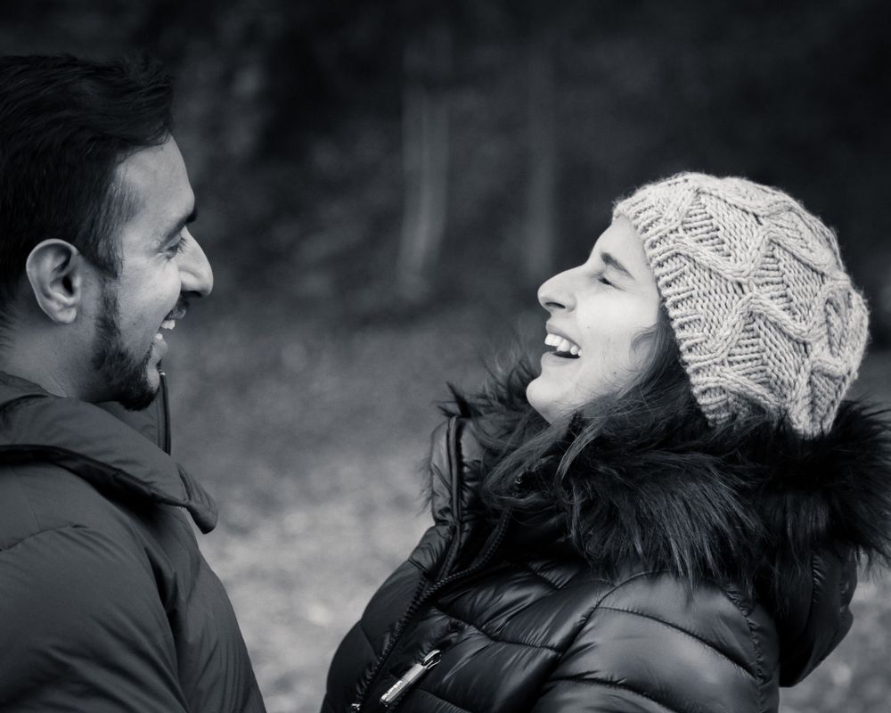 Black and white portrait of joyful couple in winter wear sharing a laugh.