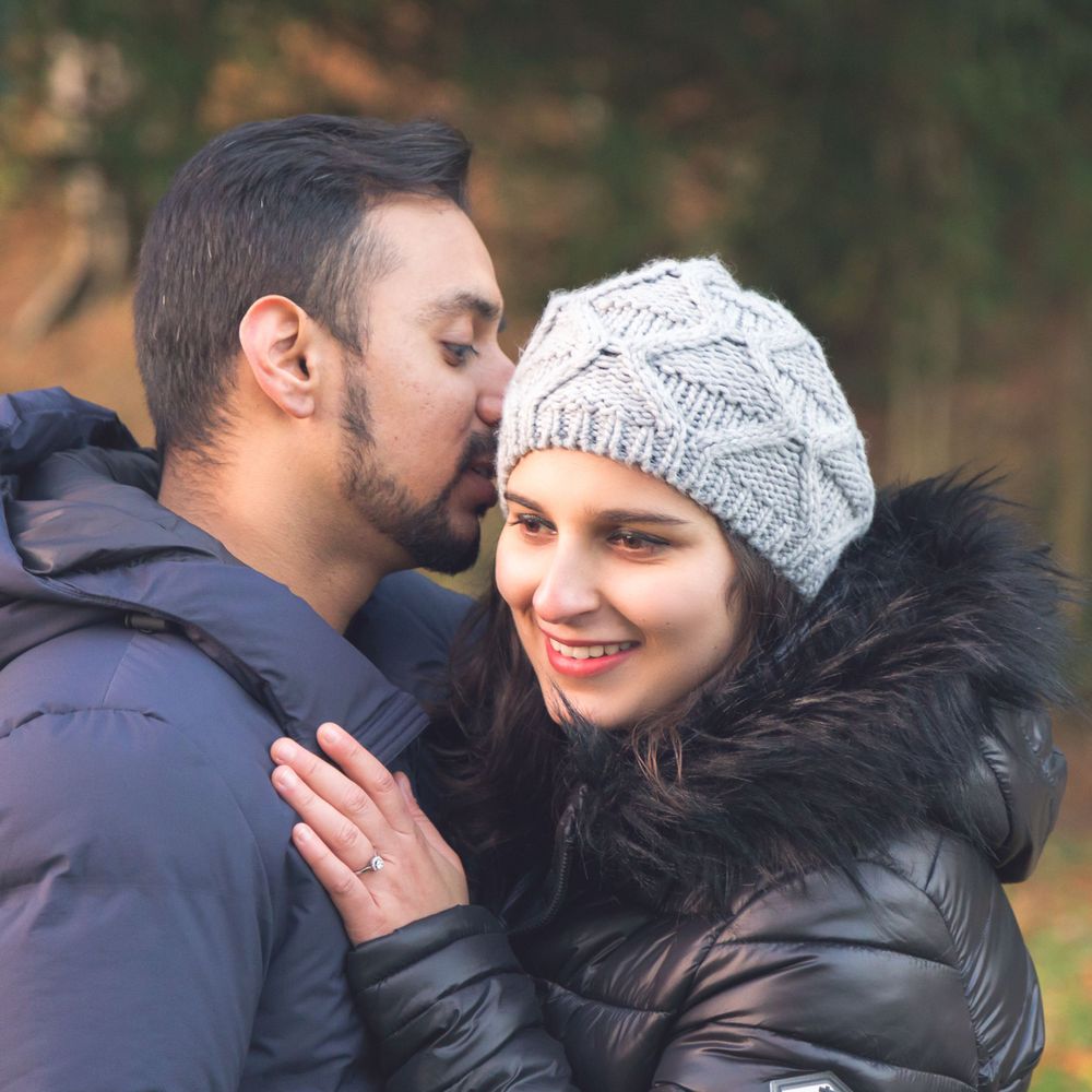 Tender moment between couple in winter jackets and knit hat during autumn photoshoot.