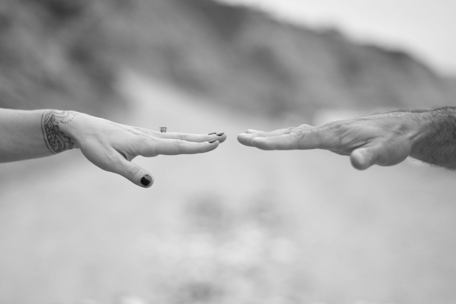 Series of black and white images showing hands reaching towards each other in an emotional gesture.