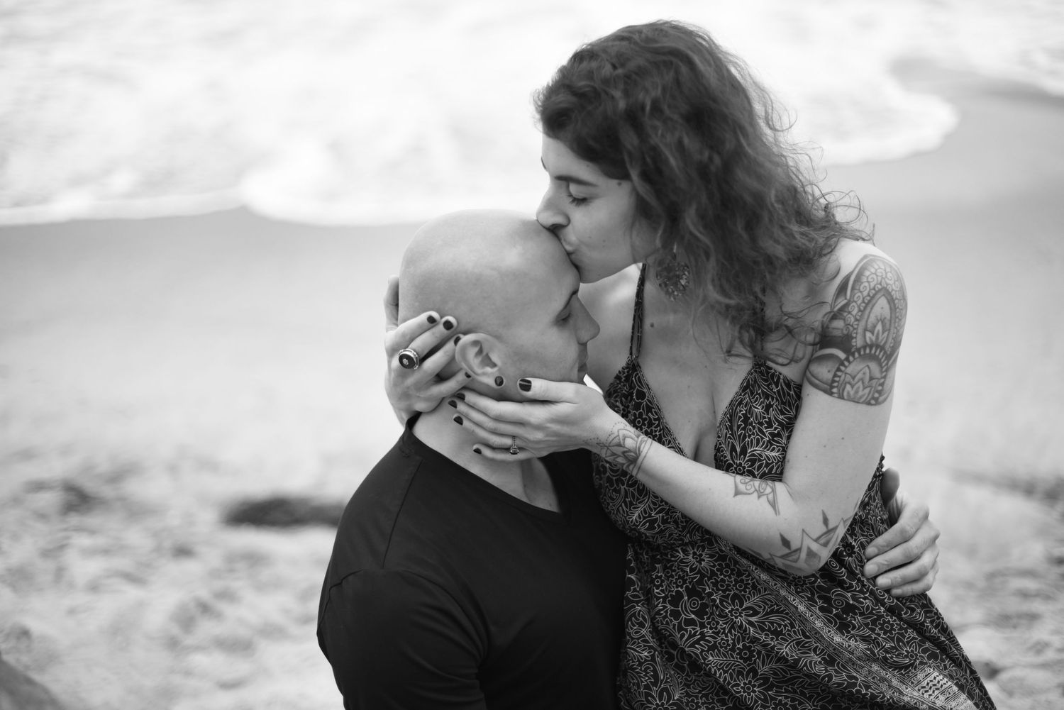 An intimate black and white beach portrait capturing a romantic moment.