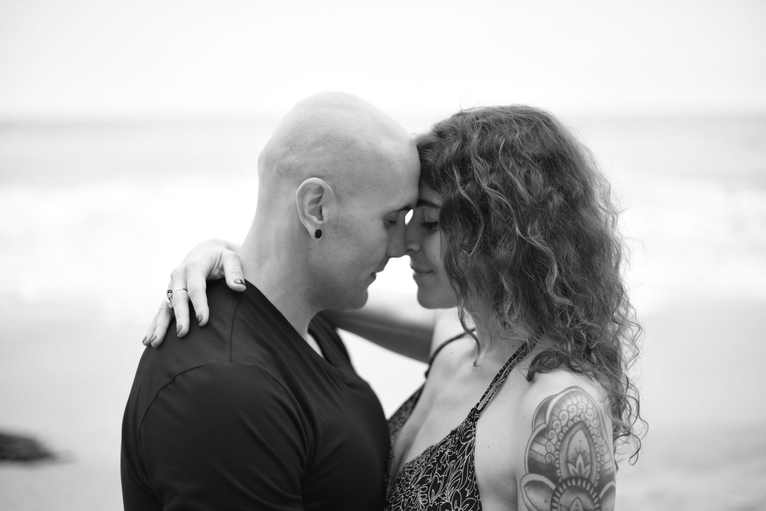 Black and white portraits of a couple sharing intimate moments by the seaside.