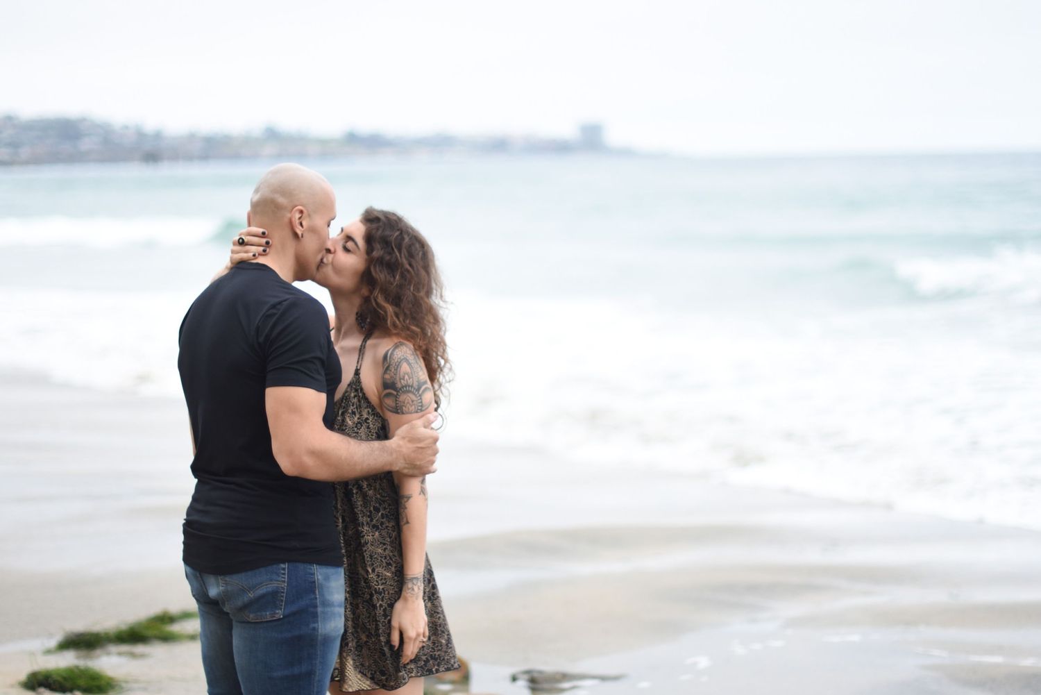 A tender romantic moment shared between two people on a misty beach.