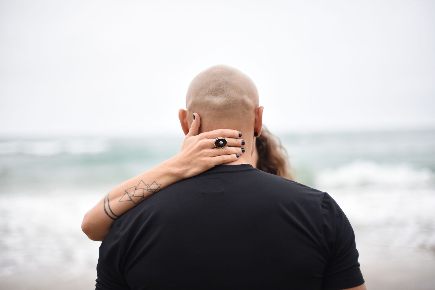 A rear view showing an intimate embrace against an ocean backdrop.