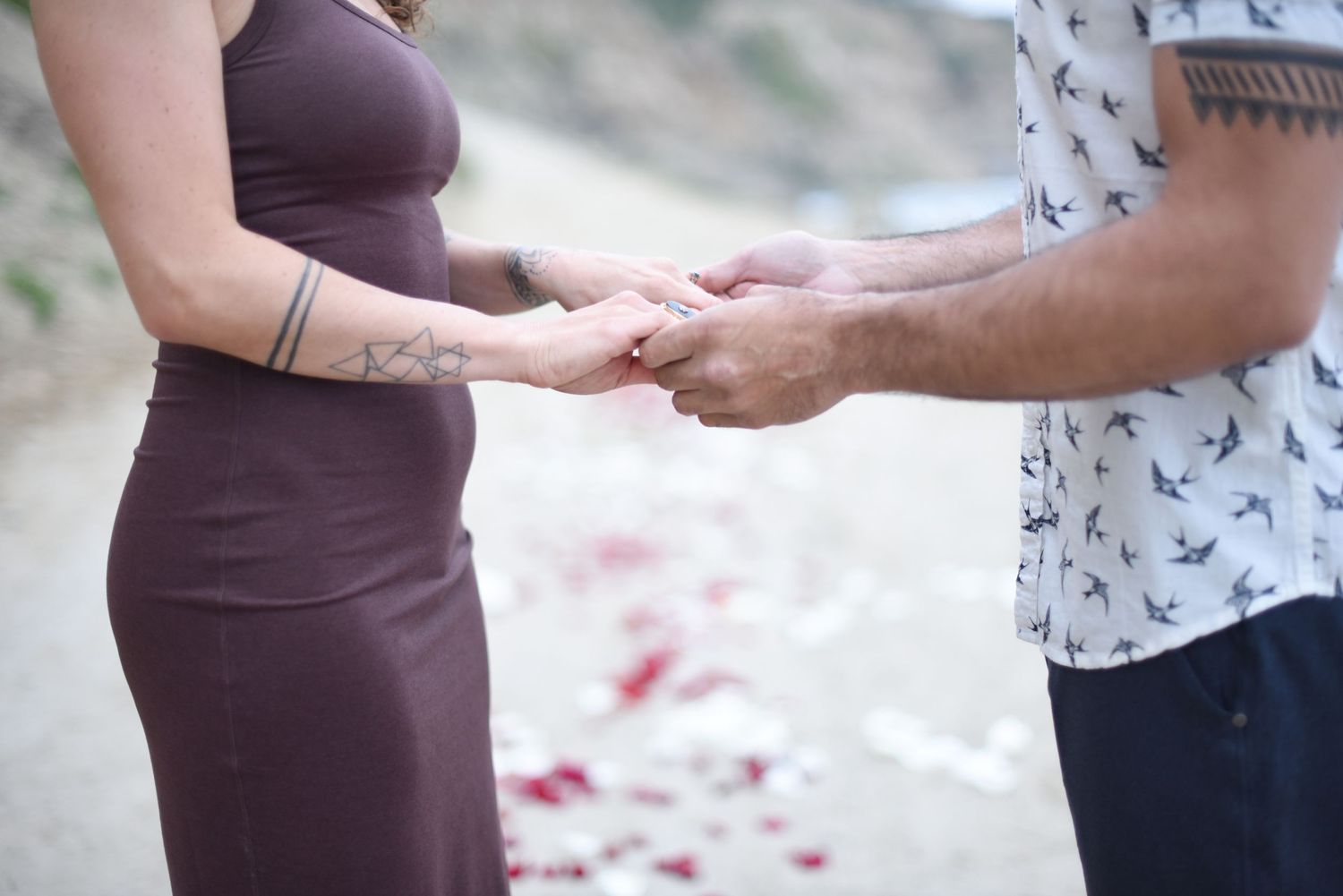 Close-up shots of hands touching and showing affection against a blurred coastal background.