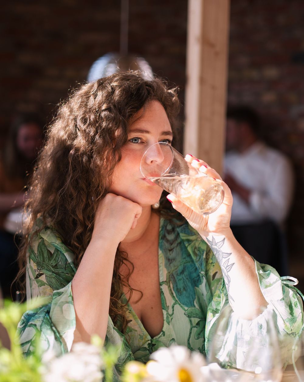 Guest in green dress enjoying a drink at an elegant table setting.