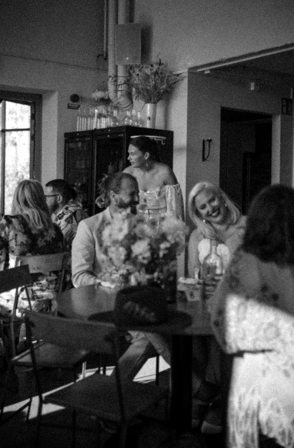 Black and white photo of wedding reception guests gathered around dining tables.